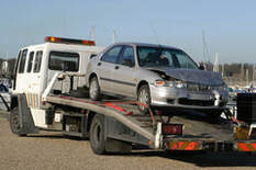 silver car being towed by white tow truck